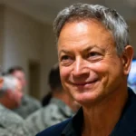 Gary Sinise smiling during a military event for Gary Sinise Net Worth
