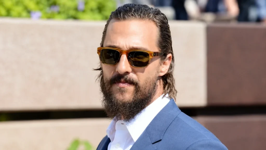 Matthew McConaughey Net Worth portrait wearing sunglasses and a blue suit