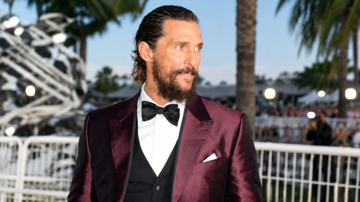Matthew McConaughey Net Worth portrait wearing a burgundy tuxedo at an outdoor event