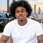 Kam Patterson Net Worth featuring Kam Patterson in a white T-shirt seated in a luxury interior with a black sports car and city skyline.